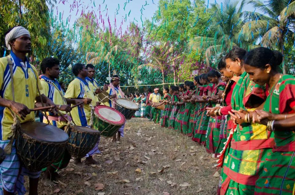 Tribal Women Performing Ritual Dance with Decorated Pots Traditional tribal women in red and white sarees participating in a cultural procession, balancing decorated pots on their heads